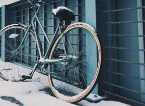 a-bike-covered-in-snow-parked-against-a-fence